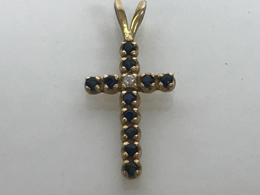 JUST ADDED - 14k Yellow Gold Cross With (11) Prong Set Saphire Like Stones And Clear Stone In Center Split Bale 3/4'L 0.5g [Photo 1]