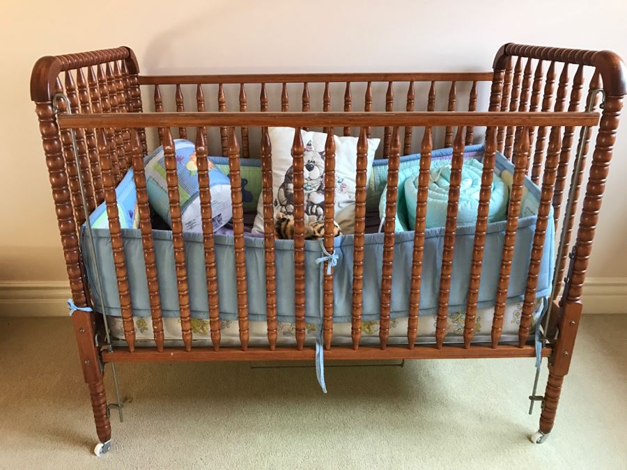 Vintage Wooden Nockonwood Baby Drop Side Crib With Various Baby Crib Bumbers, Bedding, And Other Items Photographed In Crib [Photo 1]