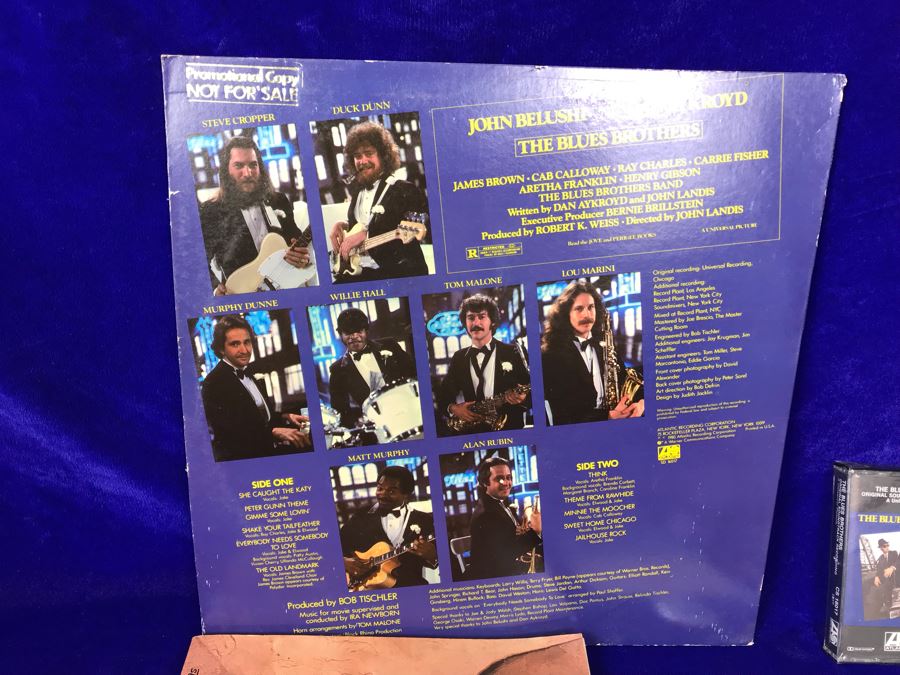 Vintage 1980 The Blues Brothers Movie Memorabilia Lot: Promo Vinyl Record, Sealed Cassette Tape, Button, 1979 Movie Concert Sticker, Blues Brothers Album Sticker, Bluesmobile Die-Cast Metal Replica Car On Damaged Card, And Private Perigee Book [Photo 9]