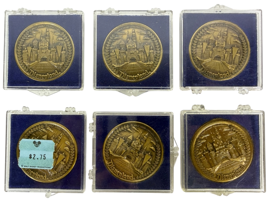(6) Vintage Walt Disney Productions Bronze Disneyland Commemorative Medallion Featuring Sleeping Beauty Castle And Five Themed Lands In Plastic Display Cases